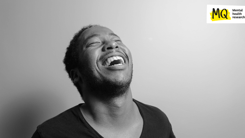 A monochrome image of a man throwing his head back in laughter