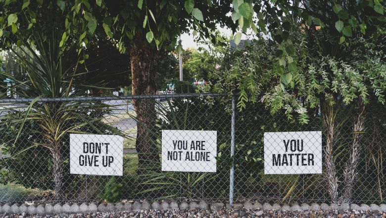 signs behind fence like "don't give up"