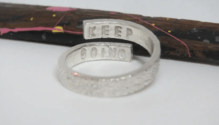 A silver ring with the message 'keep going' inscribed inside